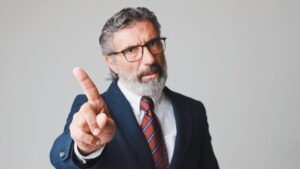 Middle-aged businessman waving his finger, gesture of disagreement looking at the camera