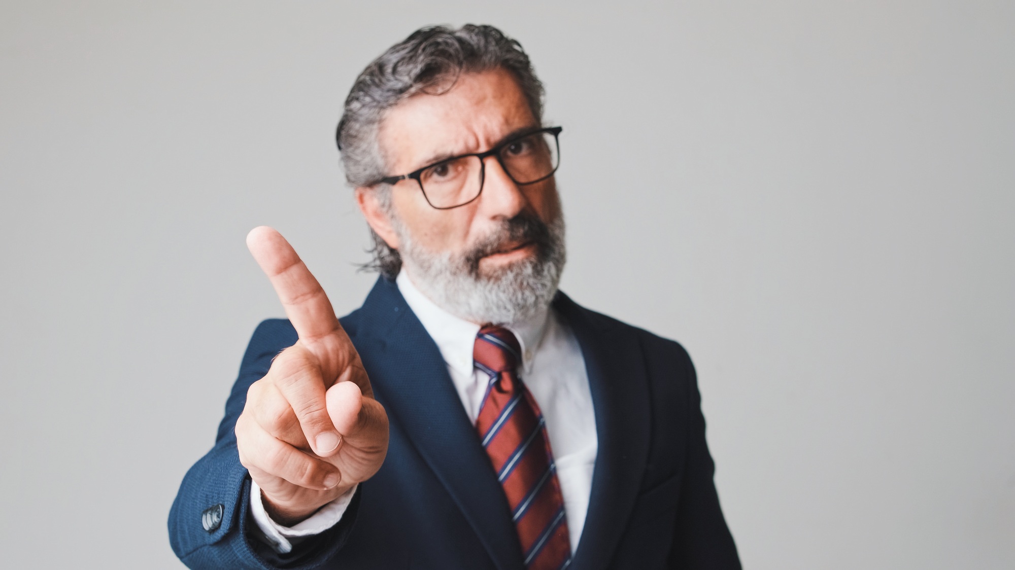 Middle-aged businessman waving his finger, gesture of disagreement looking at the camera